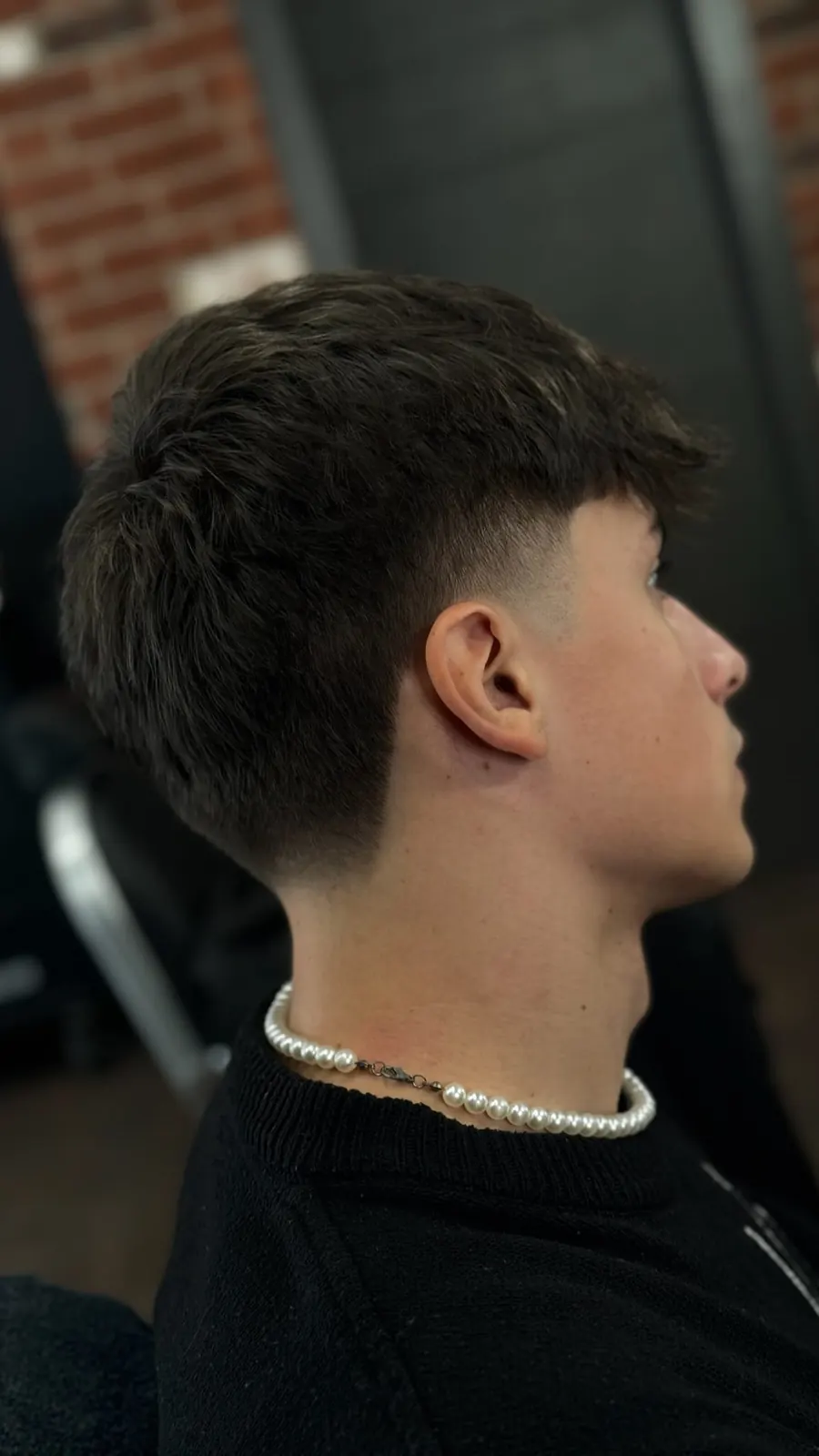 Low fade visto di profilo, con collana di perle